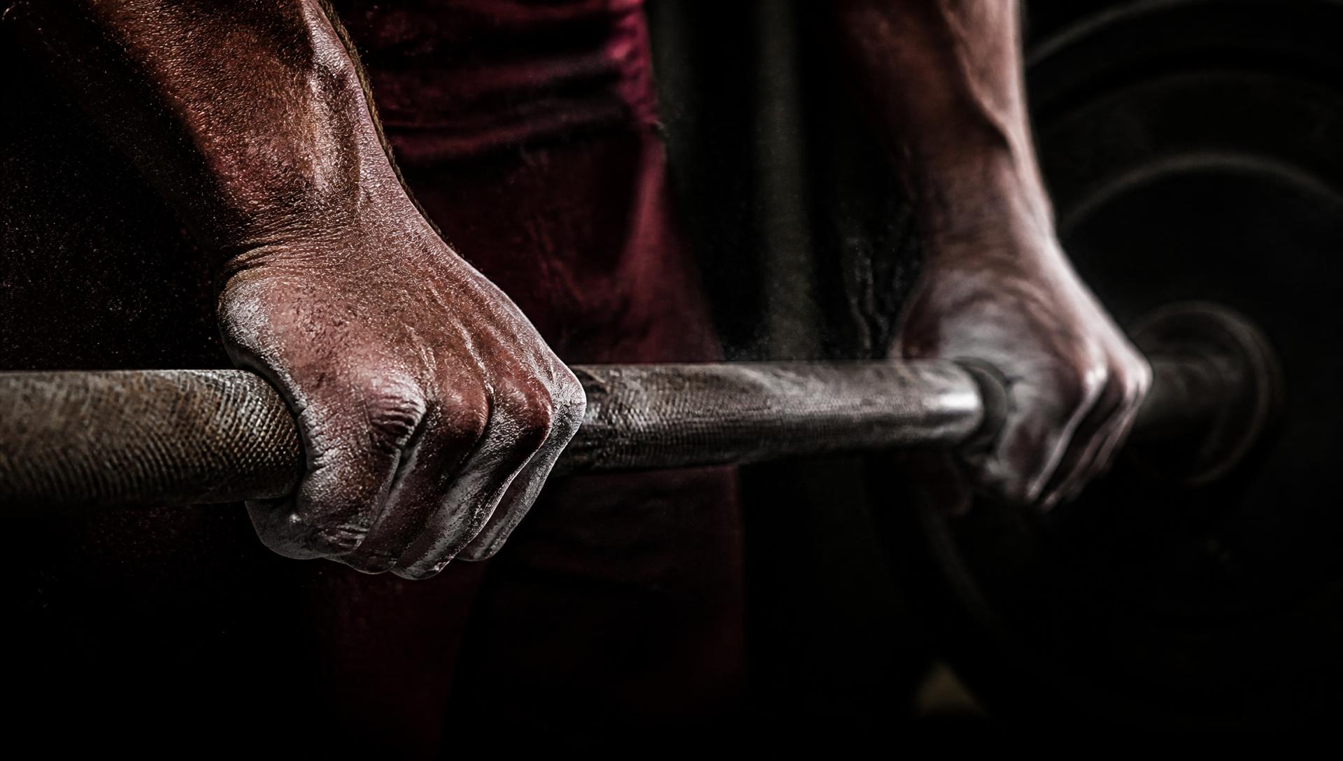 Chalked hands gripping a barbell